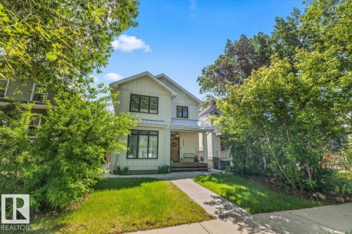 White vertical siding exterior with contrasting black window frames, a prominent front gable, and a metal awning over the entry - 10641 126 Street, Edmonton, AB 