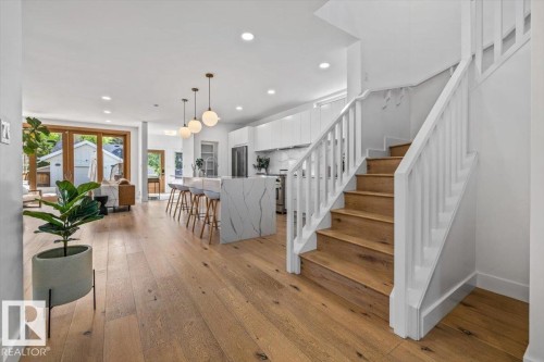 Light wood-finish flooring throughout, complemented by a white staircase with wood treads - 10641 126 Street, Edmonton, AB 
