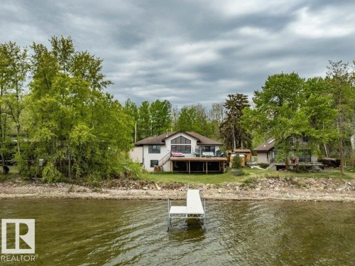 Stone paver patio featuring a built-in fire pit, surrounded by decorative rock landscaping perfect for winding up your fun filled day on the water! - 275 Poplar Crescent, Rural Wetaskiwin County, AB - Outdoor With Deck Patio Veranda