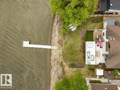 Waterfront property featuring a private dock, expansive patio, and lush green lawn - 275 Poplar Crescent, Rural Wetaskiwin County, AB - Outdoor