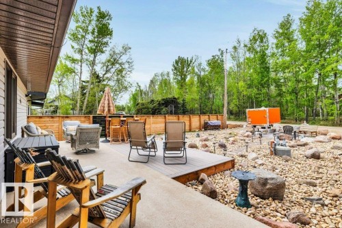 Expansive outdoor living area featuring a concrete patio, wood-finish decking, and a rock-landscaped yard - 275 Poplar Crescent, Rural Wetaskiwin County, AB - Outdoor With Deck Patio Veranda