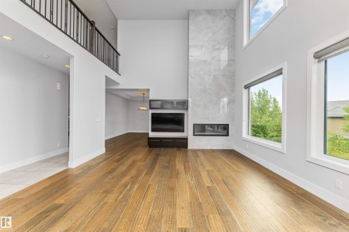 Double-height living area featuring a full-height tiled fireplace, built-in entertainment center, and expansive windows - 3310 Watson Bay, Edmonton, AB 