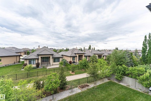 Rear exterior featuring a manicured lawn, dark metal fencing, and mature landscaping - 3310 Watson Bay, Edmonton, AB 