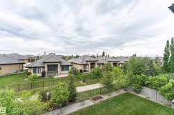 Rear exterior featuring a manicured lawn, dark metal fencing, and mature landscaping - 