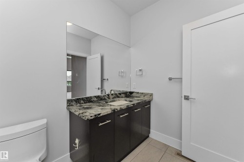 Contemporary bathroom featuring a dark wood-finish vanity with a stone countertop, an undermount sink, and a large wall-mounted mirror - 3310 Watson Bay, Edmonton, AB 