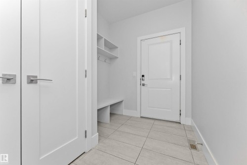 Entryway featuring light-toned tile flooring and a built-in storage bench with shelving and coat hooks - 3310 Watson Bay, Edmonton, AB 