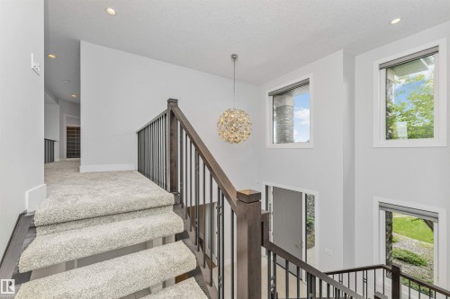 Staircase featuring dark wood-finish newel posts, wrought iron balusters, and light-toned carpeting - 3310 Watson Bay, Edmonton, AB 