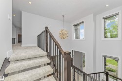 Staircase featuring dark wood-finish newel posts, wrought iron balusters, and light-toned carpeting - 