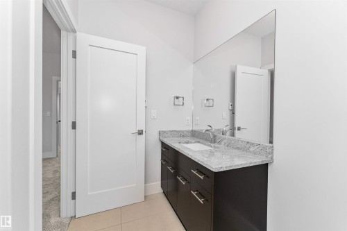 Bathroom vanity featuring a light-toned countertop, dual rectangular sinks, and a full-width mirror - 3310 Watson Bay, Edmonton, AB 