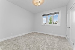 Carpeted room featuring a large window with blinds, white trim, a flush mount ceiling light, and a white interior door with a silver handle - 