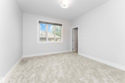 Neutral-toned room featuring light gray carpeting, white baseboards, and a white ceiling with a flush-mount light fixture - 