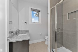 Bathroom featuring a glass-enclosed shower, tiled flooring, vanity with granite countertop and integrated sink, and a framed window - 