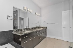 Spacious bathroom featuring a dual vanity with a patterned countertop, dual undermount sinks, and polished chrome faucets - 