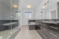 Spacious bathroom featuring a frameless glass shower enclosure, a built-in soaking tub, a dual vanity with a patterned countertop, dark wood-finish cabinetry, and chrome fixtures - 