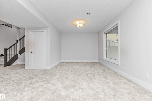 Spacious room featuring light-toned carpet flooring, neutral painted walls, and white baseboards - 3310 Watson Bay, Edmonton, AB 