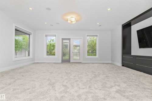 Spacious room featuring plush carpeting, a built-in entertainment center with integrated storage, and multiple windows - 3310 Watson Bay, Edmonton, AB 