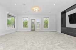 Spacious room featuring plush carpeting, a built-in entertainment center with integrated storage, and multiple windows - 