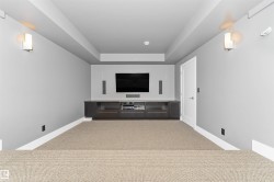 Dedicated media room featuring a large mounted display, integrated sound system, and a built-in media console with storage - 