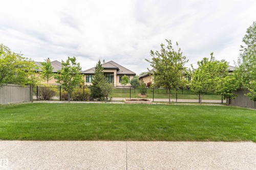 Expansive green lawn bordered by a low metal fence and mature trees - 3310 Watson Bay, Edmonton, AB 