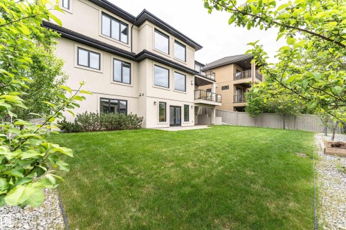 Three-story stucco exterior with black-framed windows, ground-level patio, and upper balcony with glass railings - 3310 Watson Bay, Edmonton, AB 