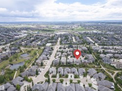Aerial view of a residential neighborhood featuring detached homes with grey roofs and mature landscaping - 