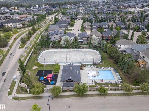 Community recreation area featuring a multi-sport court, a playground with rubberized surfacing, a swimming pool, and a dedicated building with a dark shingle roof - 3310 Watson Bay, Edmonton, AB 