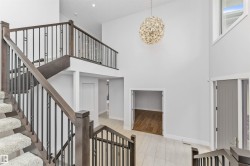 Two-story foyer featuring a contemporary chandelier, a multi-level staircase with wood-finish handrails and black metal balusters, and light-toned tile flooring - 