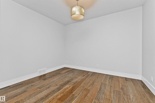 Room featuring wood-finish plank flooring, crisp white baseboards, and neutral wall paint - 3310 Watson Bay, Edmonton, AB 