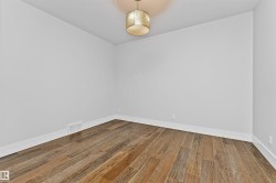 Room featuring wood-finish plank flooring, crisp white baseboards, and neutral wall paint - 
