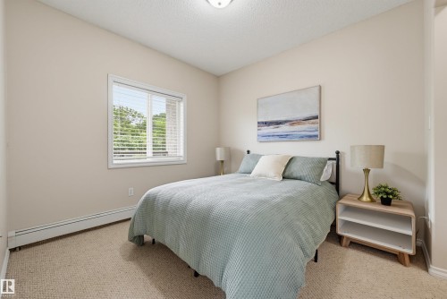 Carpeted room with a large window featuring horizontal blinds - 203 10719 80 Avenue, Edmonton, AB 