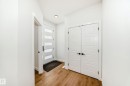 Entryway featuring a contemporary white door with frosted glass panels, wood-finish flooring, recessed lighting, and a double-door closet with black hardware - 341 Roberts Wynd, Leduc, AB 