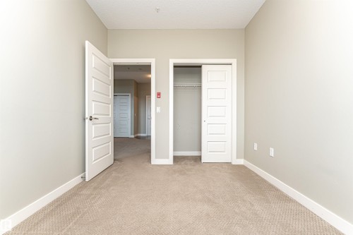 Carpeted room featuring light neutral wall tones and white baseboards - 505 1230 Windermere Way, Edmonton, AB 