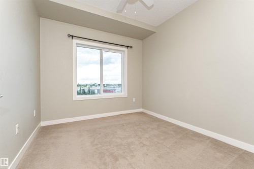Large window with a black curtain rod and white trim, offering expansive exterior views - 505 1230 Windermere Way, Edmonton, AB 
