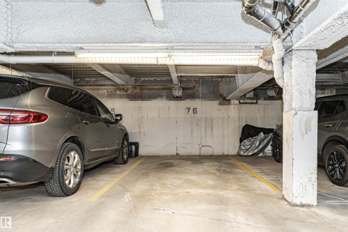 Designated parking space with concrete flooring, exposed utility piping, and overhead fluorescent lighting - 505 1230 Windermere Way, Edmonton, AB 