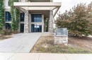 Contemporary building entrance featuring stone veneer columns, expansive windows, and a paved walkway - 505 1230 Windermere Way, Edmonton, AB 