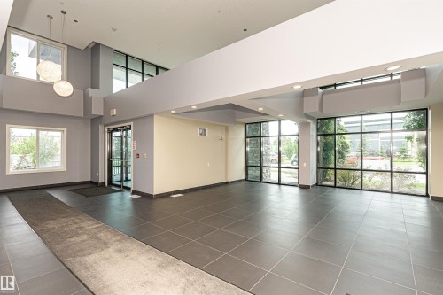 Spacious lobby featuring large format tile flooring, expansive window walls, and recessed lighting - 505 1230 Windermere Way, Edmonton, AB 