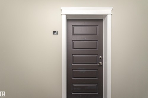 Dark panel door with white trim set into a light neutral wall - 505 1230 Windermere Way, Edmonton, AB 