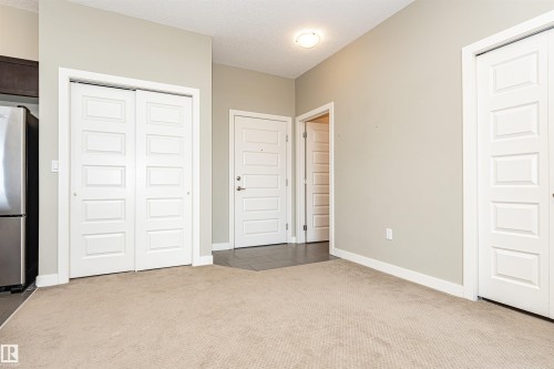 Entryway featuring neutral wall paint, light beige carpet, and white trim - 505 1230 Windermere Way, Edmonton, AB 