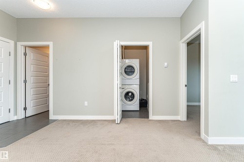 Dedicated laundry area featuring stacked appliances - 505 1230 Windermere Way, Edmonton, AB 