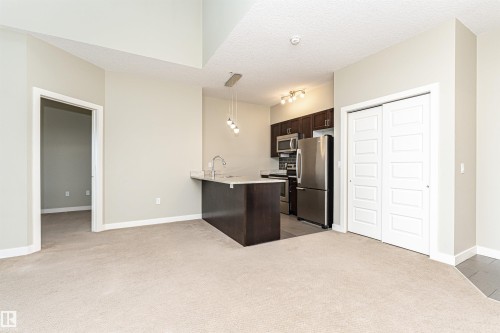 Kitchen with dark wood cabinetry, stainless steel appliances, and a light-toned countertop - 505 1230 Windermere Way, Edmonton, AB 