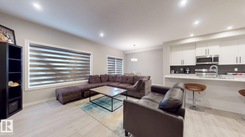Open-concept living space with light wood-finish flooring, recessed lighting, and expansive windows featuring horizontal blinds - 607 31 Avenue, Edmonton, AB 