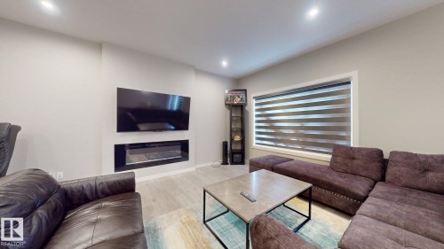 Living area featuring a mounted entertainment display, an integrated linear fireplace, and wood-finish flooring - 607 31 Avenue, Edmonton, AB 