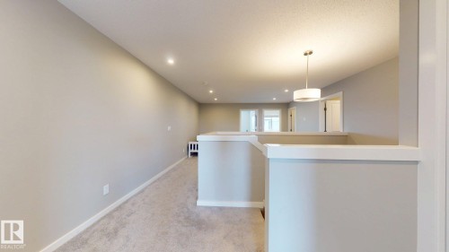 Upper-level landing featuring neutral carpeting, light gray wall tones, recessed lighting, white trim work, and a contemporary drum pendant light fixture - 607 31 Avenue, Edmonton, AB 