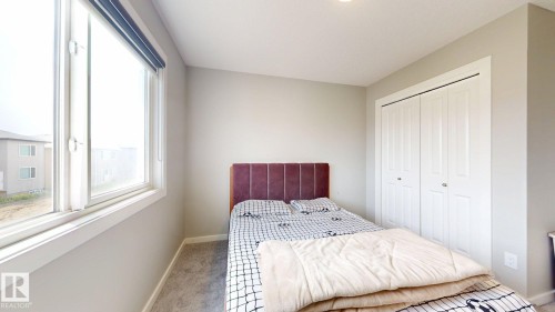 Light-filled room featuring a large window with roller shades, neutral gray walls, and plush gray carpeting - 607 31 Avenue, Edmonton, AB 