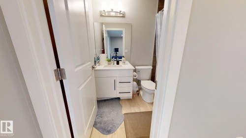 Bathroom featuring a white vanity with integrated sink, chrome faucet, wall-mounted mirror, and overhead light fixture - 607 31 Avenue, Edmonton, AB 