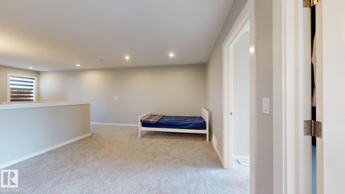Spacious carpeted room featuring recessed lighting, a half-wall partition, and a window with horizontal blinds - 607 31 Avenue, Edmonton, AB 