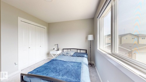 Carpeted room featuring a white bi-fold closet and a large window with roller shades - 607 31 Avenue, Edmonton, AB 