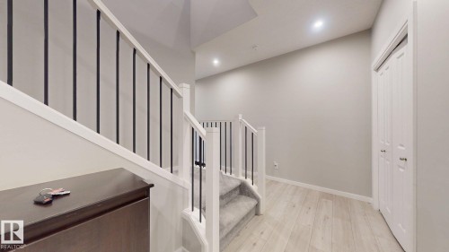 Staircase with white newel posts and black metal balusters, featuring light wood-finish flooring, recessed lighting, and white bi-fold doors - 607 31 Avenue, Edmonton, AB 