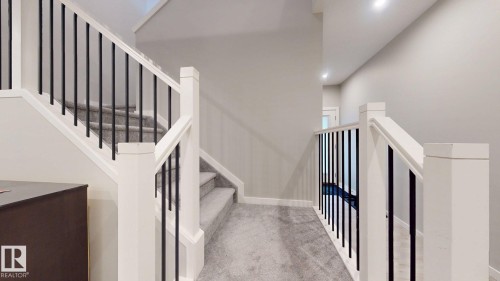 Staircase featuring white newel posts and handrails with contrasting black metal balusters - 607 31 Avenue, Edmonton, AB 