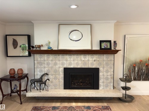 Fireplace featuring a patterned tile surround, a dark wood mantel, and a built-in firebox - 14016 85 Avenue, Edmonton, AB 